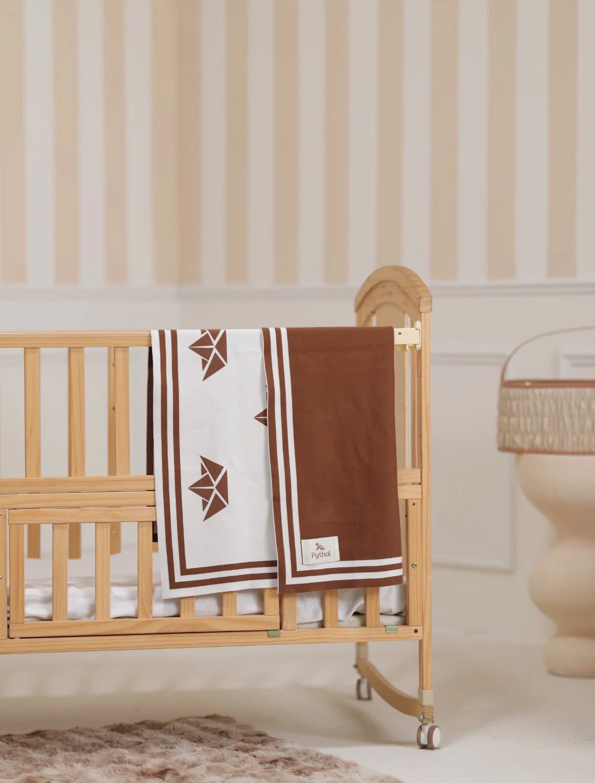 A Pythal brown and cream graphic blanket draped over a wooden nursery crib.